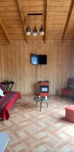 Habitación con sofá, mesa y TV. en Cabañas Kaykun, en Puerto Octay