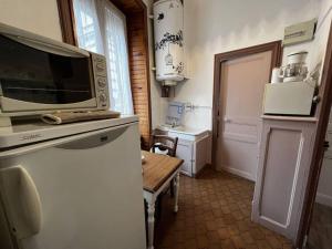 una cocina con un microondas encima de un refrigerador en Le nid douillet Rustique Linge fourni, en La Bourboule 8 fotos más