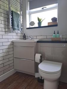 een badkamer met een toilet, een wastafel en een raam bij Cosy cottage near Alton Towers in Rocester