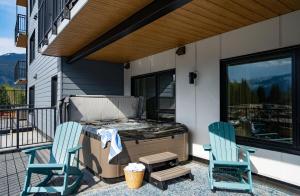 two chairs and a grill on a patio with two chairs at Sea Eagles Landing by Revelstoke Vacations in Revelstoke