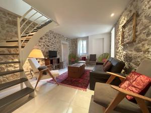 sala de estar con escalera y pared de piedra en Gîte de 12 personnes au cœur d'un domaine viticole en Gruissan