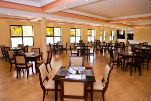 a dining room with tables and chairs and windows at Rossina Living in Naivasha