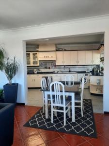 a kitchen with white cabinets and a table and chairs at Casa das Camélias in Aveiro