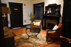 Sparrow Grove Manor في مونرو: غرفة معيشة مع طاولة وكرسيين ومدفأة