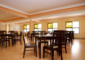 a dining room with tables and chairs and windows at Rossina Living in Naivasha
