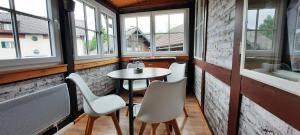 ein kleiner Tisch und Stühle in einem Zimmer mit Fenstern in der Unterkunft Hexenhäuschen in Bad Goisern