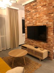 een woonkamer met een bakstenen muur en een flatscreen-tv bij Solankowe Zacisze Boho Inowrocław in Inowrocław