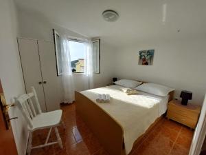 a bedroom with a bed and a chair and a window at Apartments Jerko in Ražanj