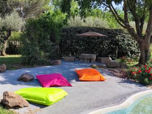 Trois coussins colorés sur une terrasse avec un parasol dans l'établissement Villa Pio, à Roquebrune-sur Argens