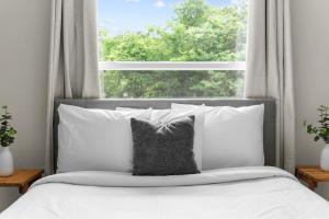 Un dormitorio con una cama con almohadas blancas y una ventana en 10 Min to Downtown-Modern in Magic City-Both Units, en Birmingham
