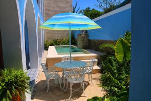 - une table et des chaises avec un parasol sur la terrasse dans l'établissement Boutique Casa Azuli Santiago, à Mérida