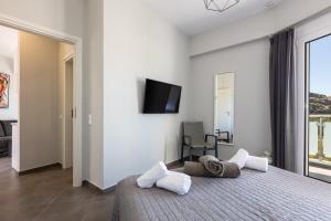 een slaapkamer met een bed en een tv aan de muur bij Nereides - Skinaria Beach Apartment in Damnoni