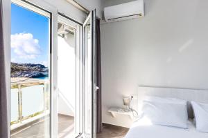een slaapkamer met een bed en een groot raam bij Nereides - Skinaria Beach Apartment in Damnoni