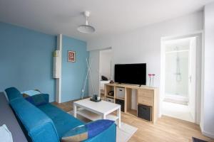 ein Wohnzimmer mit einem blauen Sofa und einem TV in der Unterkunft Appartement avec terrasse et parking, à Meaux in Meaux