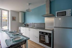 eine Küche mit weißen Schränken und blauen Wänden in der Unterkunft Appartement avec terrasse et parking, à Meaux in Meaux