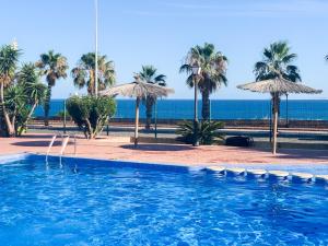 a swimming pool with umbrellas and the ocean at Apartamento La Menia - Cabo Roig in Orihuela Costa