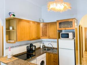 a kitchen with wooden cabinets and a white refrigerator at Apartamento La Menia - Cabo Roig in Orihuela Costa