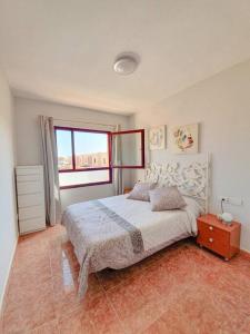 a bedroom with a large bed and a window at Piscina & Wifi. SUNNY apartement, swimming pool. in Caleta De Fuste