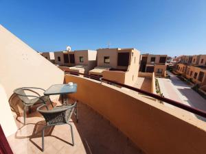 a balcony with two chairs and a table on a building at Piscina & Wifi. SUNNY apartement, swimming pool. in Caleta De Fuste