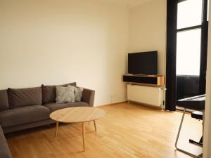 ein Wohnzimmer mit einem Sofa, einem Tisch und einem TV in der Unterkunft Stunning 1-Bedroom Apt with Breathtaking Scenery in Tórshavn