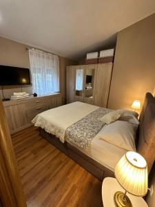 een slaapkamer met een bed en een televisie en een lamp bij Apartman Lusy in Tribunj
