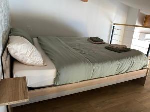 Una cama con sábanas verdes y almohadas. en Le Gîte de Maxou en Montauban