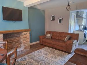 a living room with a couch and a fireplace at Cosy cottage near Alton Towers in Rocester