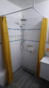 ein Bad mit einer Dusche und einem gelben Duschvorhang in der Unterkunft Chez Caroline in Basse-Terre