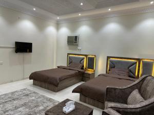 1 dormitorio con 2 camas, sofá y TV en شقق مطله على مسجد قباء, en Medina
