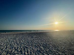 una playa de arena con el sol saliendo sobre el océano en EBBTIDE INN en St Pete Beach
