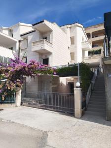 un condominio bianco con recinzione e fiori viola di Sea View House & Free Parking a Podstrana