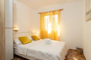 Cette chambre comprend un lit blanc avec des oreillers jaunes et une fenêtre. dans l'établissement Villa Planka Pearl, à Ražanj
