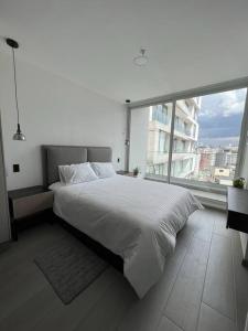 ein weißes Bett in einem Schlafzimmer mit einem großen Fenster in der Unterkunft Sky View Studio - Best Area Quito in Quito