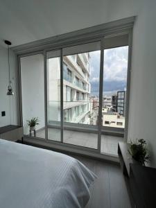 Schlafzimmer mit einem großen Fenster mit Blick auf ein Gebäude in der Unterkunft Sky View Studio - Best Area Quito in Quito