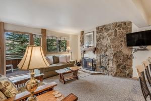ein Wohnzimmer mit einem Kamin und einer Steinmauer in der Unterkunft Laurelwood Condominiums 205 in Snowmass Village