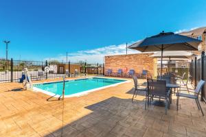 a pool with a table and chairs and an umbrella at Fairfield Inn & Suites by Marriott Corpus Christi Central in Corpus Christi