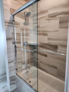 a shower with a glass door and wooden wall at The Hen Houses in Wildwood