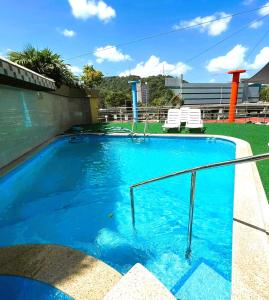 une grande piscine bleue avec deux chaises blanches dans l'établissement Hotel Casa Miller, à Panama City