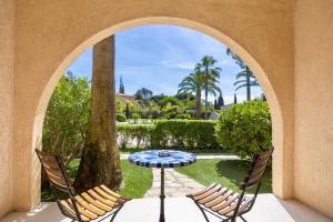 un patio con 2 sillas, una mesa y un árbol en Hotel La Garbine en Saint-Tropez