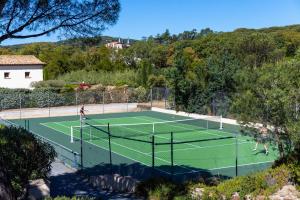 two people playing tennis on a tennis court at Hotel La Garbine in Saint-Tropez