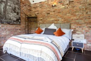 a brick walled bedroom with a bed with orange pillows at Luxury Retreat -Perfect To Explore The North Coast in Macosquin