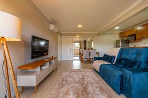 ein Wohnzimmer mit einem blauen Sofa und einem Fernseher in der Unterkunft Excelente ap em Canela - @stayhousetemporada in Canela