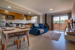 eine Küche und ein Wohnzimmer mit einem Tisch und einer Couch in der Unterkunft Excelente ap em Canela - @stayhousetemporada in Canela