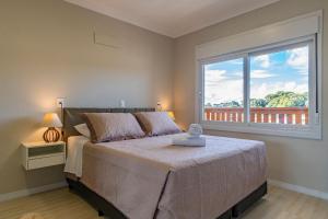 ein Schlafzimmer mit einem Bett und einem großen Fenster in der Unterkunft Excelente ap em Canela - @stayhousetemporada in Canela