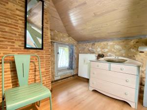 Zimmer mit einer Kommode und einem grünen Stuhl in der Unterkunft Le chant des oiseaux in Tourliac