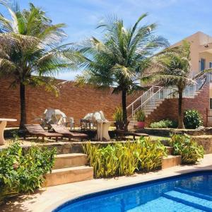 un complejo con piscina y palmeras en Hana Praia Hotel, en Camocim