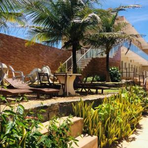 a park with benches and palm trees and a building at Hana Praia Hotel in Camocim