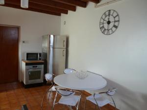 a kitchen with a white table and chairs and a refrigerator at Les Sureaux Le Gite 3 étoiles par CDT24 in Le Pizou