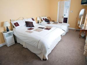 um quarto com 2 camas com lençóis brancos e um espelho em Hawthorn View Bed and Breakfast em Thurles