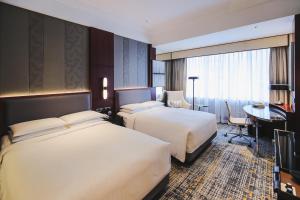 a hotel room with two beds and a desk at Shanghai Marriott Marquis City Centre in Shanghai